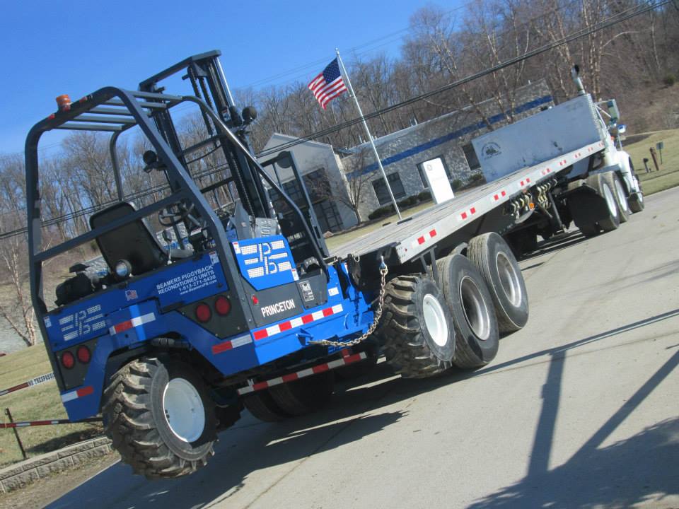 blue truck mounted forklift on the back of a truck bed