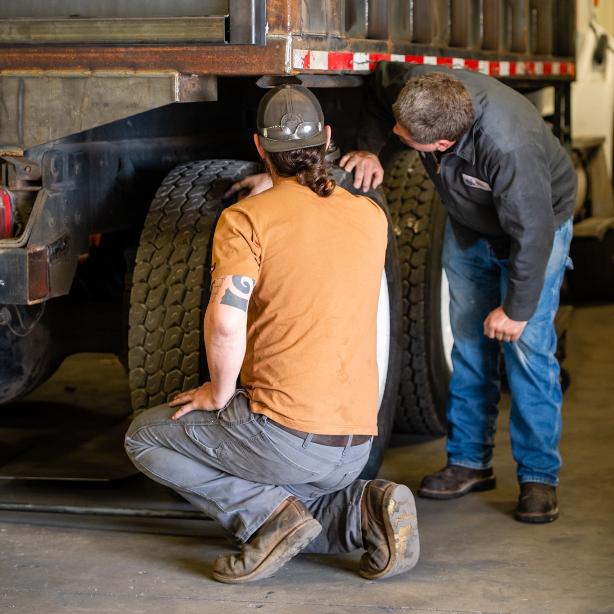two men inspecting tires on a truck